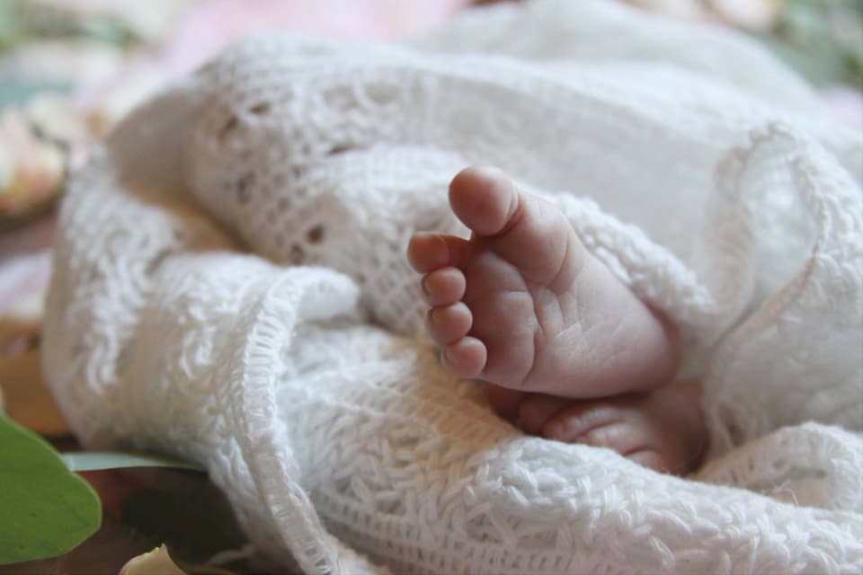 Newborn foot peeking out of a knit blanket