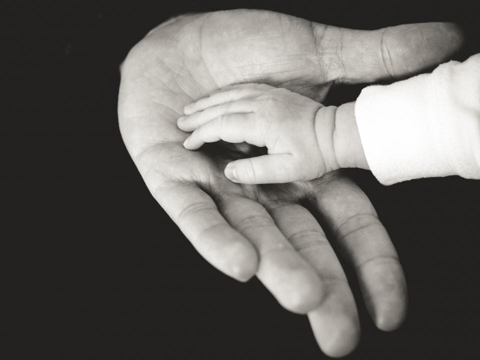 Newborn hand resting in a parent's palm