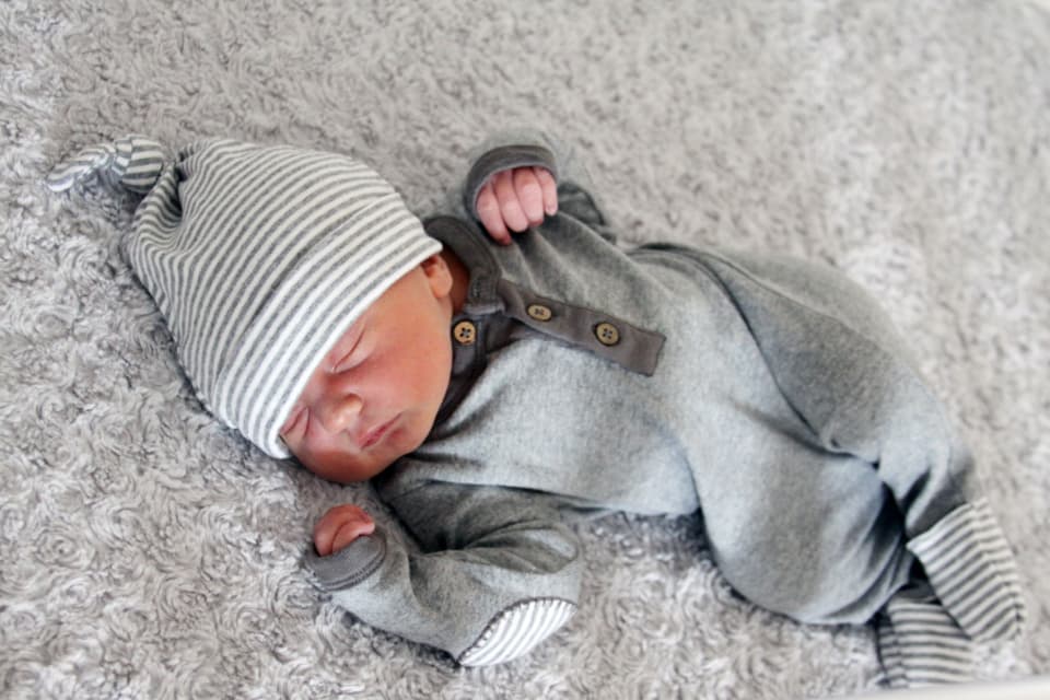 Newborn asleep in a striped knit hat