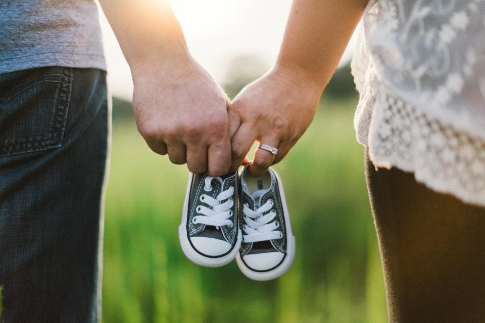 Parents holding a pair of tiny sneakers
