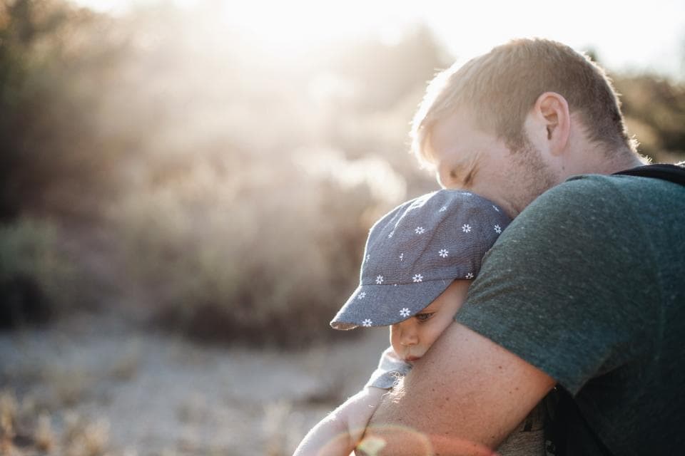 Dad cuddling his son in the sun