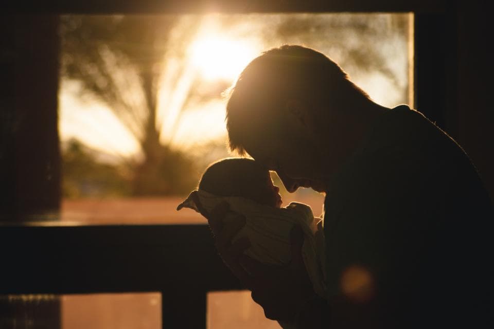 Dad holding his newborn by the window