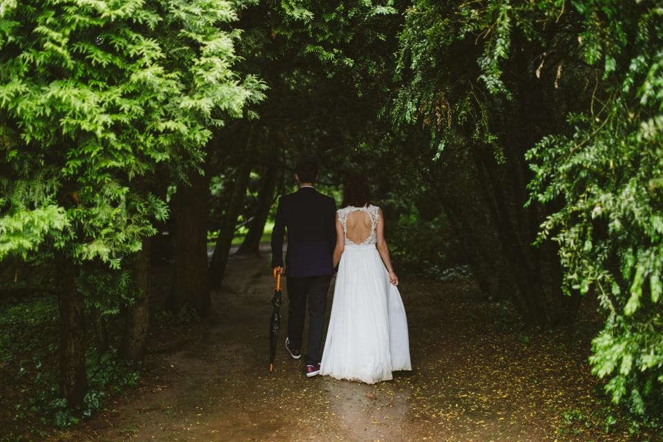 Bride and groom walking along a forest path