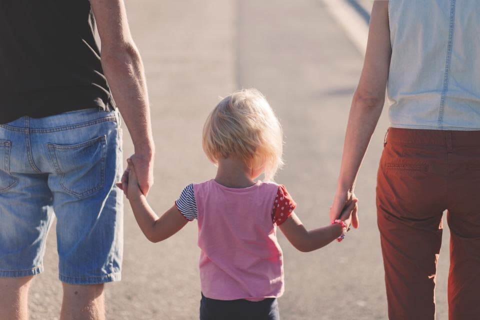 Toddler holding both parents' hands