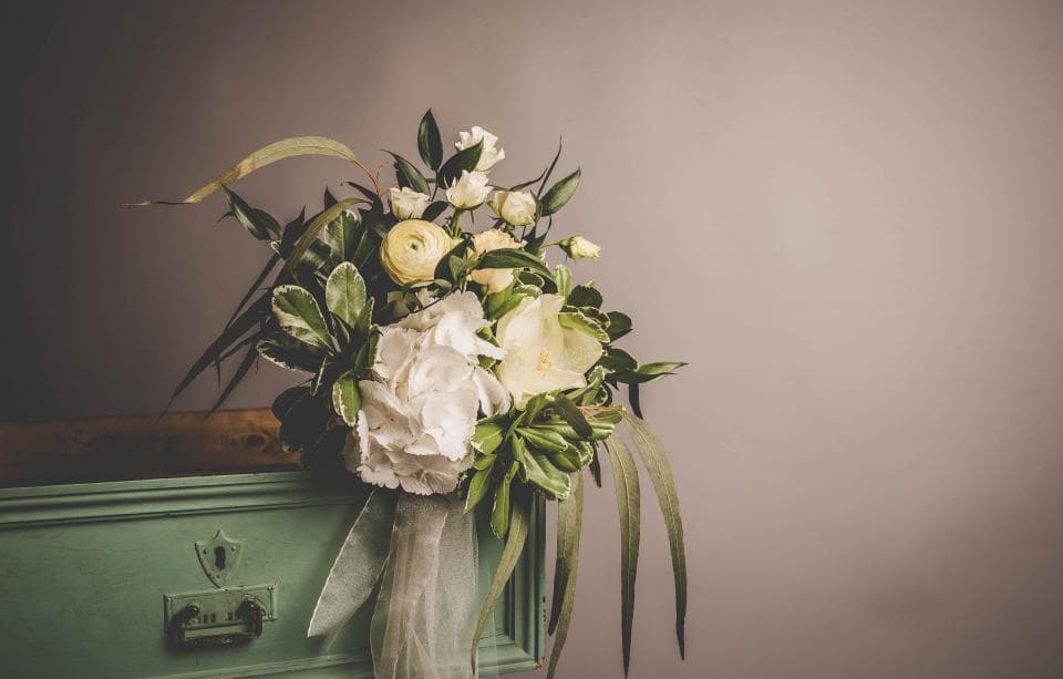 White bouquet resting on a vintage case