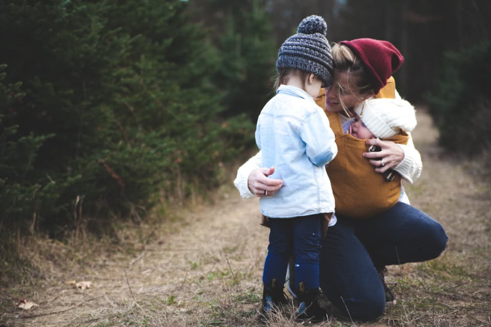 Mother hugging her little one on a woodland path